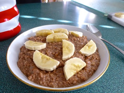 A bowl of paleo cinnamon apple oatmeal topped with chopped bananas. 