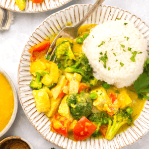 A bowl of mango chicken curry topped with white rice and garnished with cilantro.