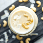 A jar of cashew coconut butter topped with raw cashews.