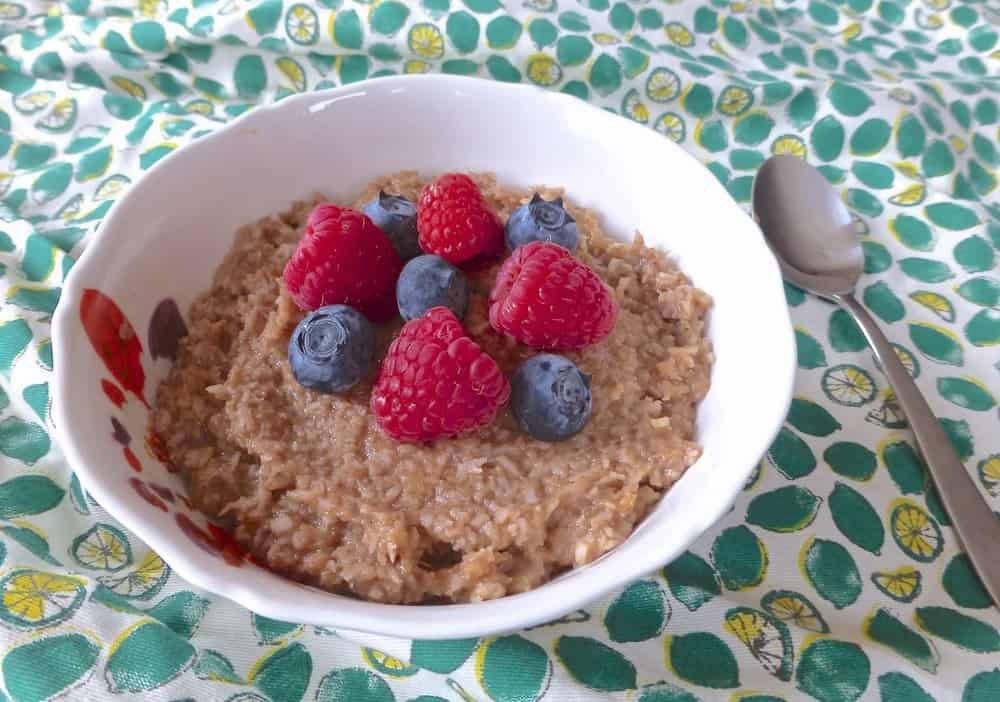 A bowl of paleo oatmeal topped with fresh blueberries and raspberries.