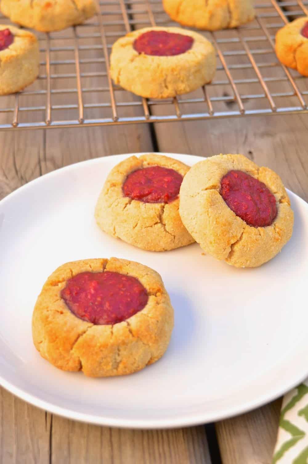 A plate full of gluten free raspberry thumbprint cookies. 