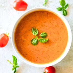 A bowl of cherry tomato soup topped with fresh basil.