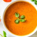 A bowl of cherry tomato soup topped with fresh basil.