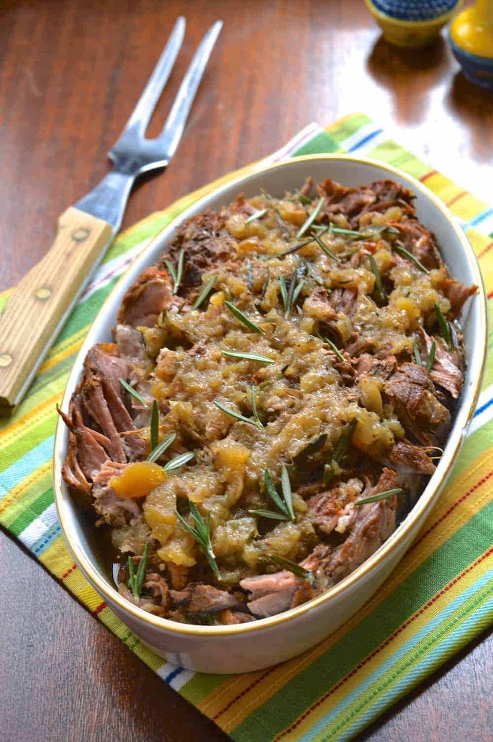A serving dish filled with a cooked apple rosemary pork roast. 