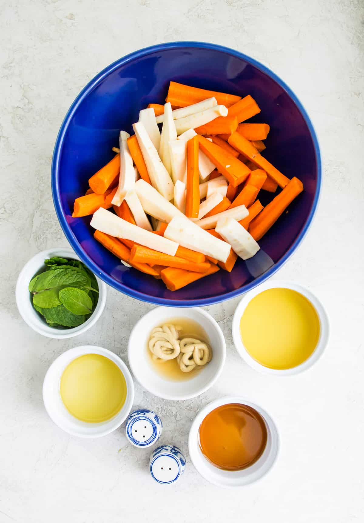 The ingredients needs to make roasted carrots and parsnips separated into bowls.