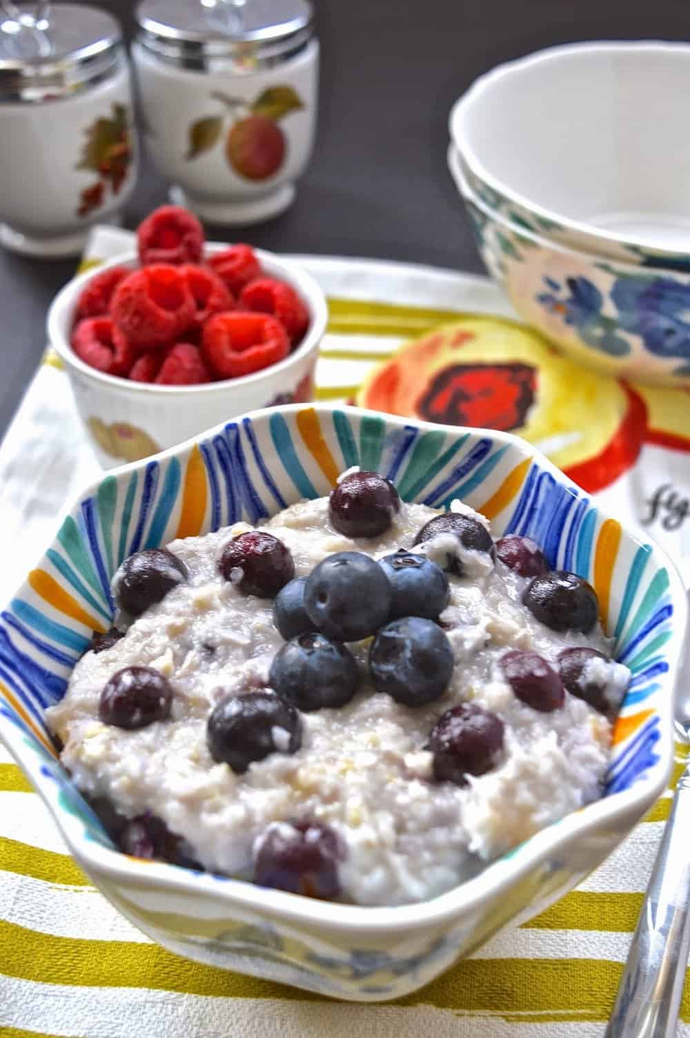 A bowl of paleo oatmeal topped with fresh blueberries and a spoon beside it.