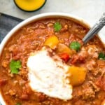 A bowl of healthy chili with ground pork topped with sour cream.