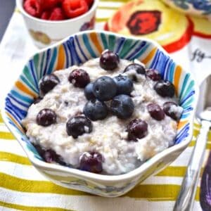 A bowl of oatmeal topped with fresh blueberries.