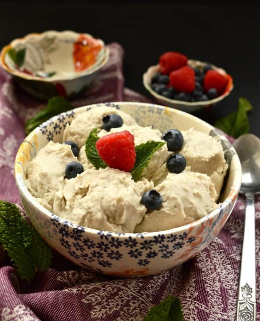 A bowl of paleo vanilla ice cream topped with blueberries and raspberries.