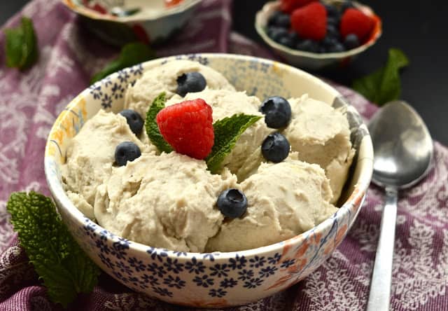 A bowl of paleo vanilla ice cream topped with blueberries and raspberries. 