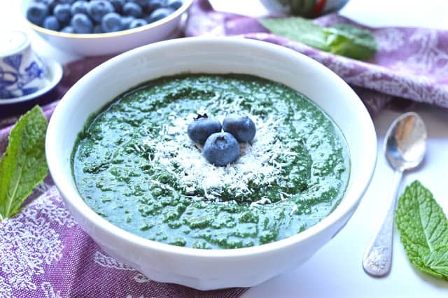 A mint smoothie breakfast bowl with a spoon beside it