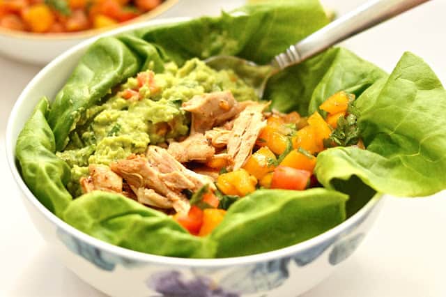A chicken burrito bowl topped with guacamole and salsa. 