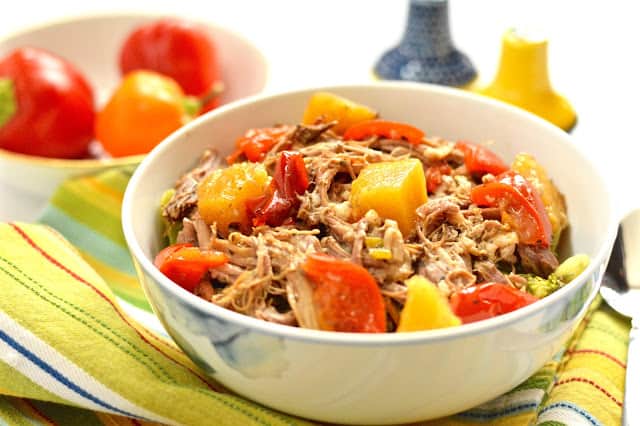 A bowl of slow cooker pineapple pork roast surrounded by a colourful napkin. 