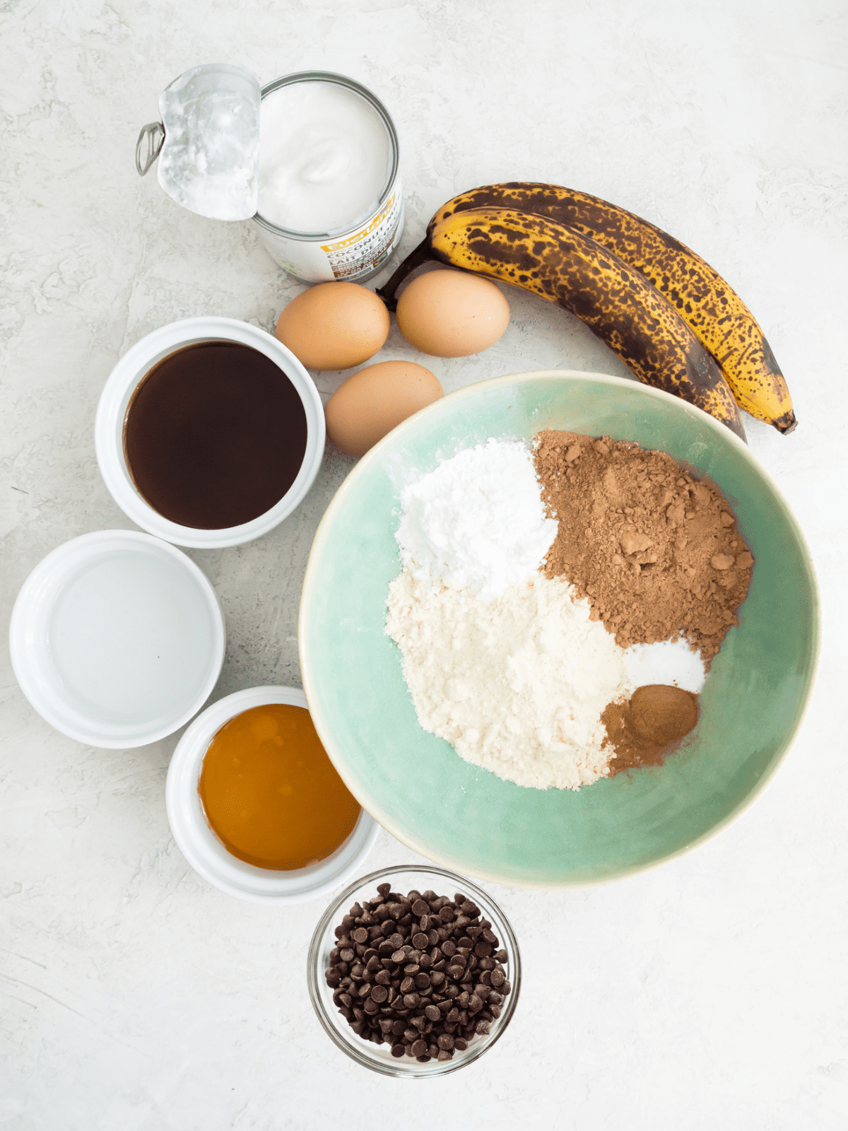 The ingredients needed to make a chocolate coffee banana bread in small bowls. 