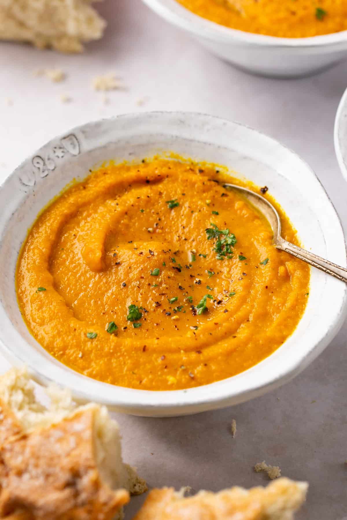 A bowl of carrot and turnip soup, garnished with fresh parsley.