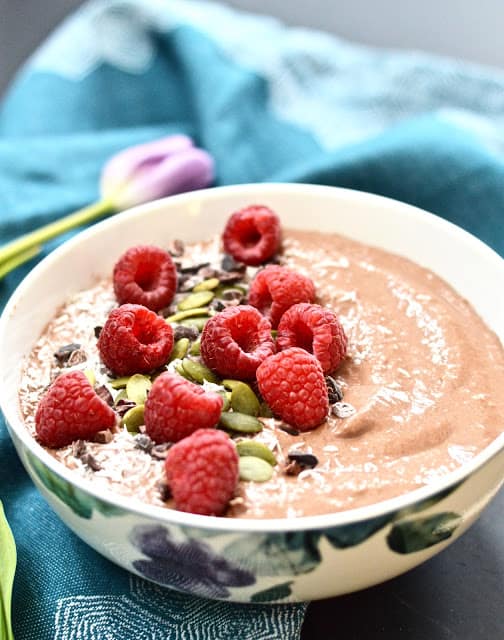 A chocolate raspberry bliss smoothie bowl topped with shredded coconut and fresh raspberries