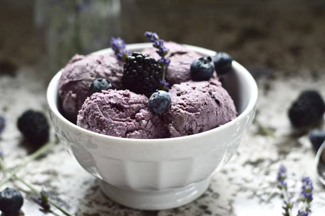 A bowl of paleo double berry coconut ice cream with blueberries on top for garnish. 