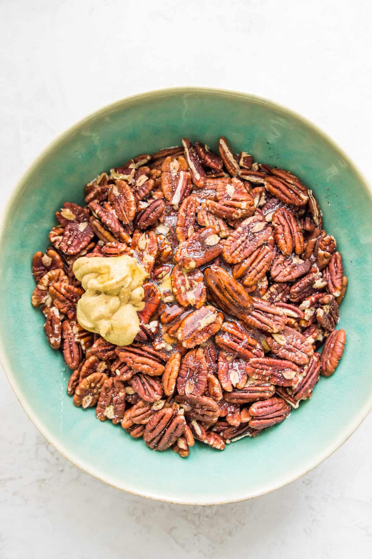 A bowl with pecans, honey and mustard in it.