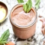 A jar of strawberry basil vinaigrette topped with fresh mint leaves.