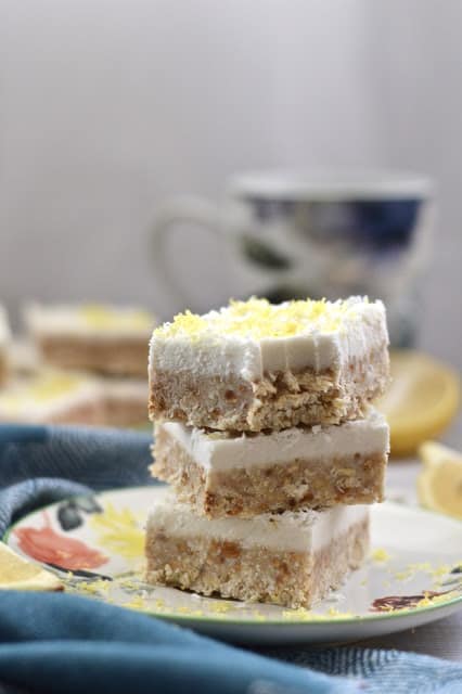 A stack of three lemon coconut cheesecake bars, and the top one has a bite out of it.