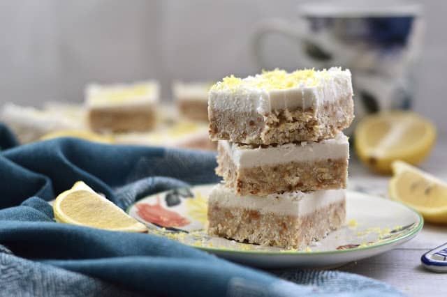 A stack of raw lemon and coconut cheesecake bars. 