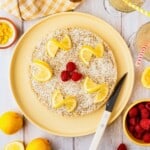 A vegan lemon cheesecake topped with shredded coconut and raspberries.