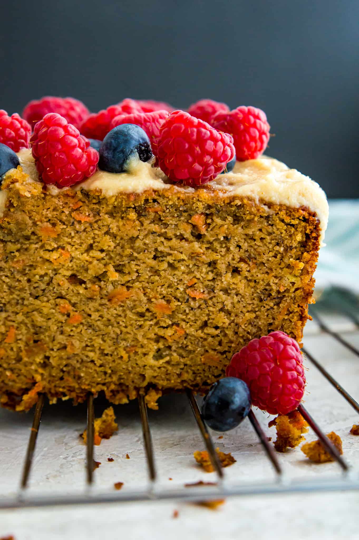 A loaf of paleo carrot cake banana bread topped with fresh blueberries and raspberries.