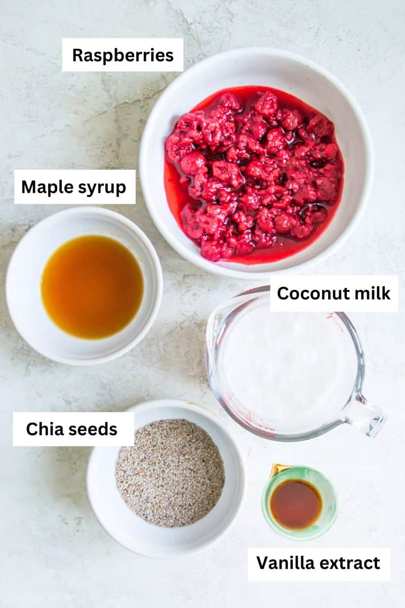 Bowls filled with different ingredients including raspberries, maple syrup, coconut milk, chia seeds and vanilla extract.