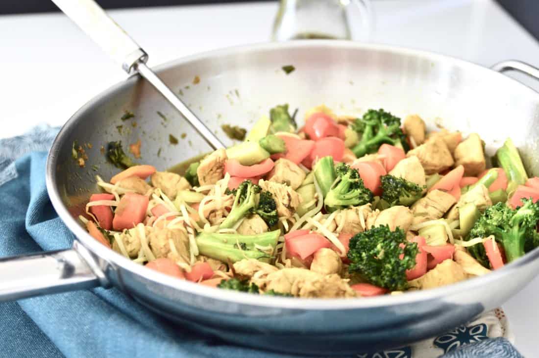 A wok filled with an orange ginger chicken stir fry with a serving spoon in it.