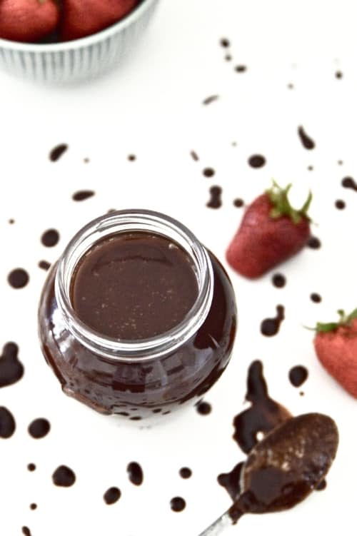 A jar of healthy chocolate sauce with a spoon beside it. 