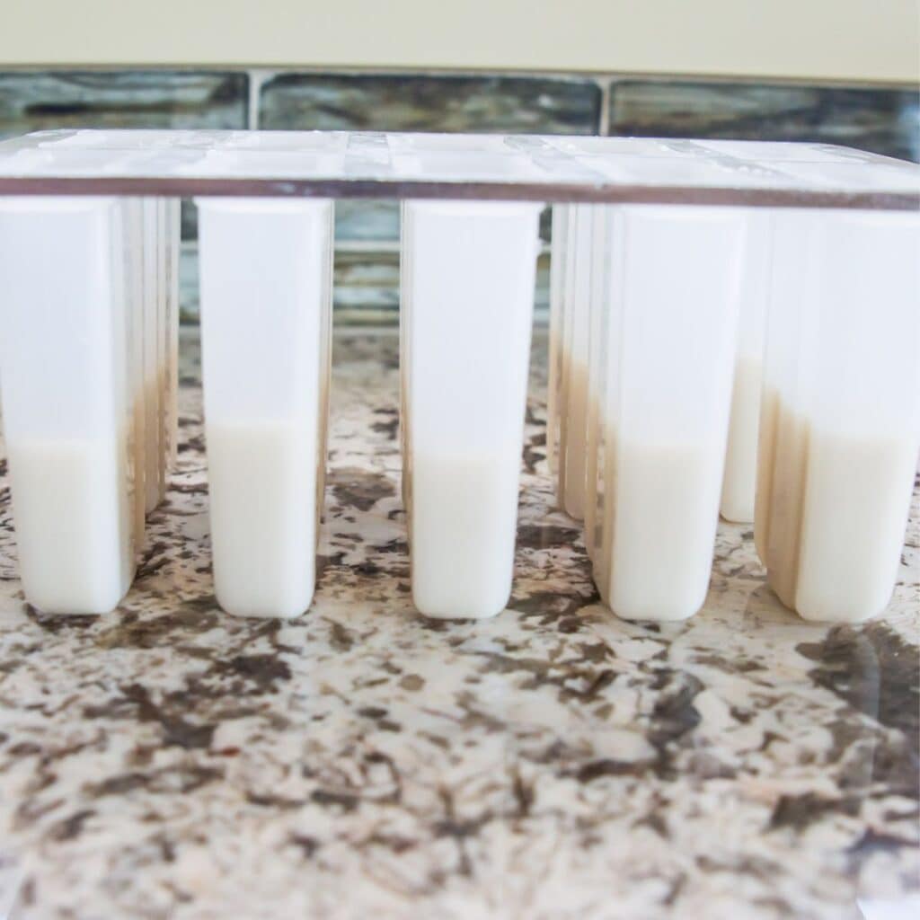A popsicle mold filled half way with a white liquid.