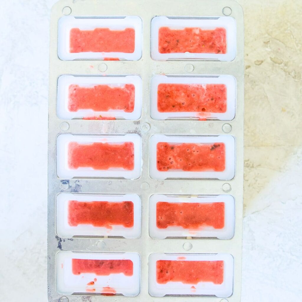 A popsicle mold filled with a red liquid.