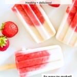 Three strawberry vanilla popsicles on a plate surrounded by fresh strawberries.