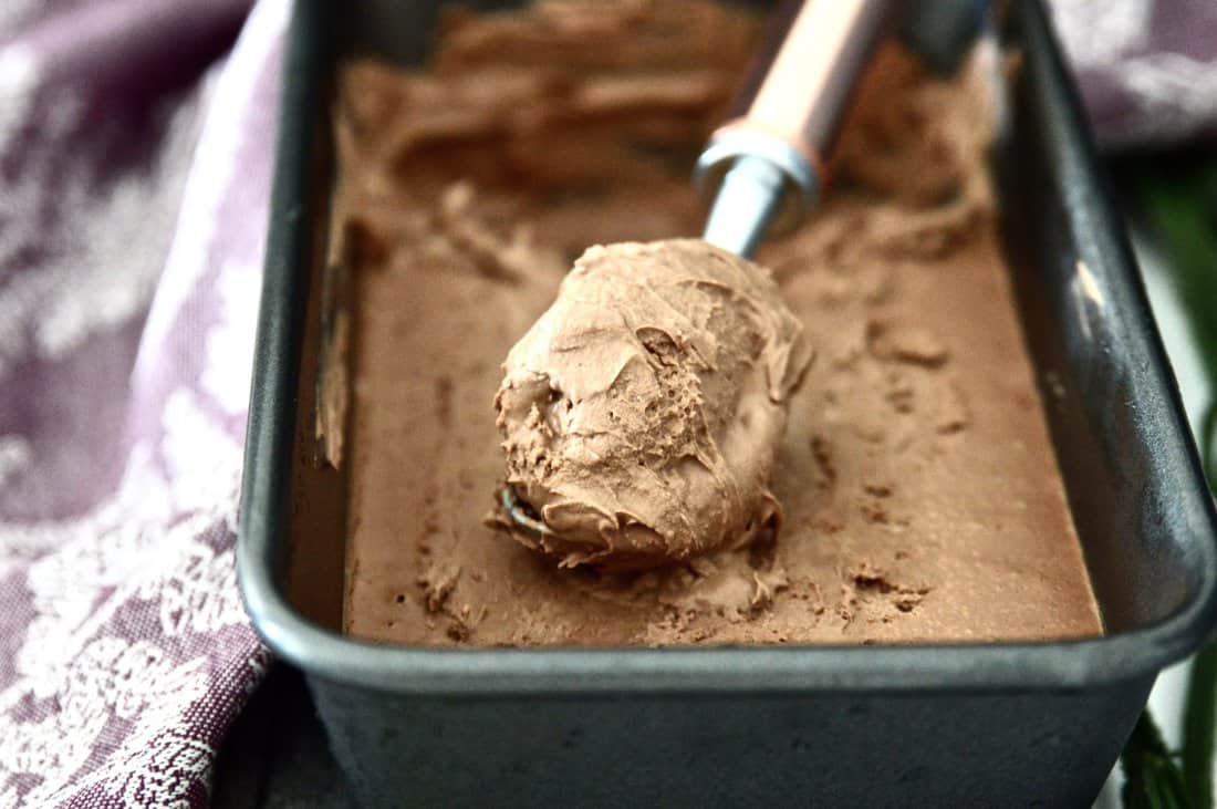 A pan filled with dairy free chocolate ice cream with an ice cream scoop in it.