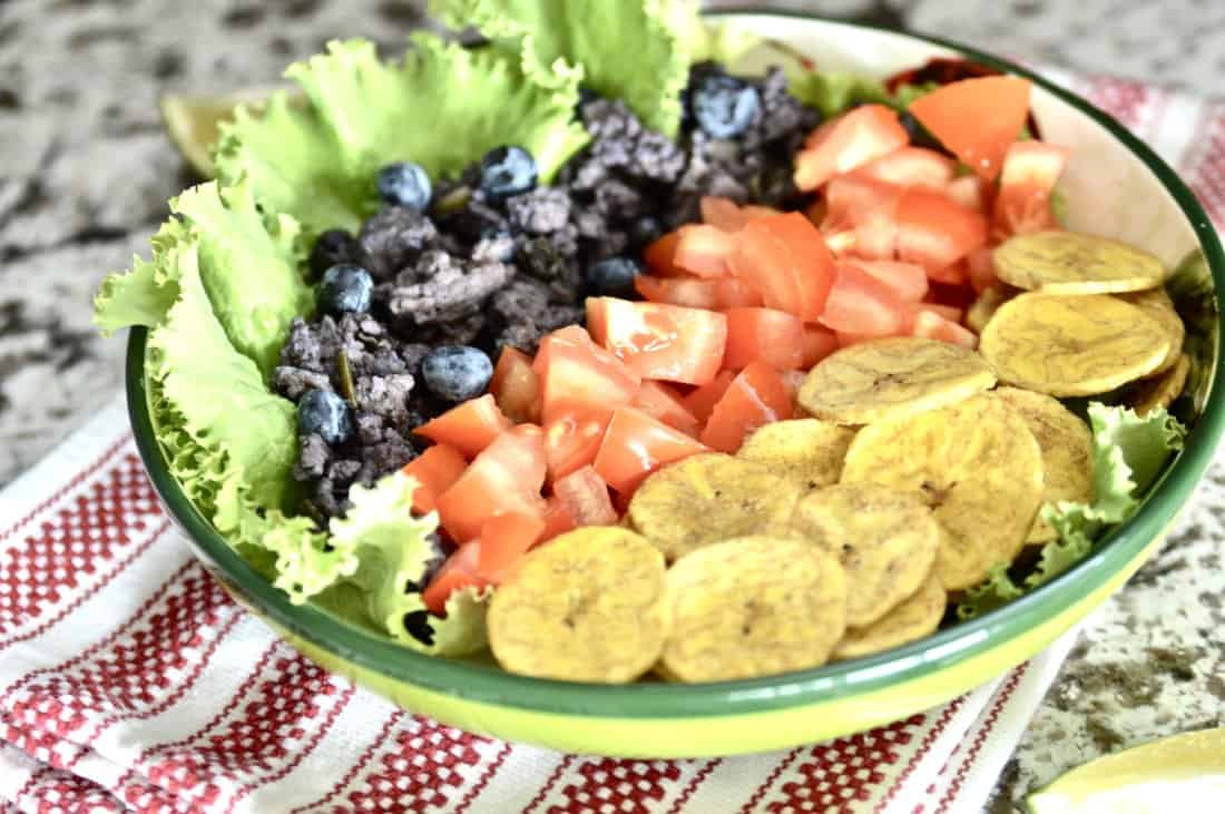 a beef and blueberry burrito bowl with tomatoes, plantains and lettuce. 
