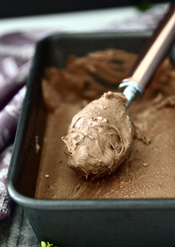 A pan of paleo chocolate ice cream with an ice cream scoop in it.