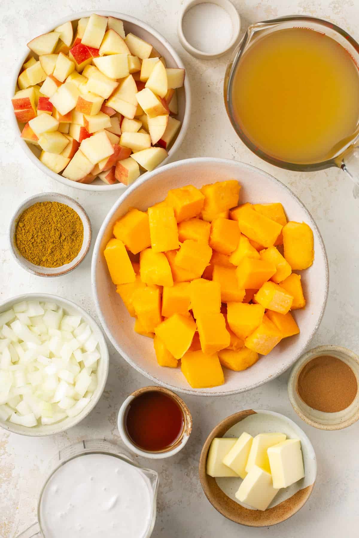The ingredients needed to make a curried butternut squash soup in small bowls. 