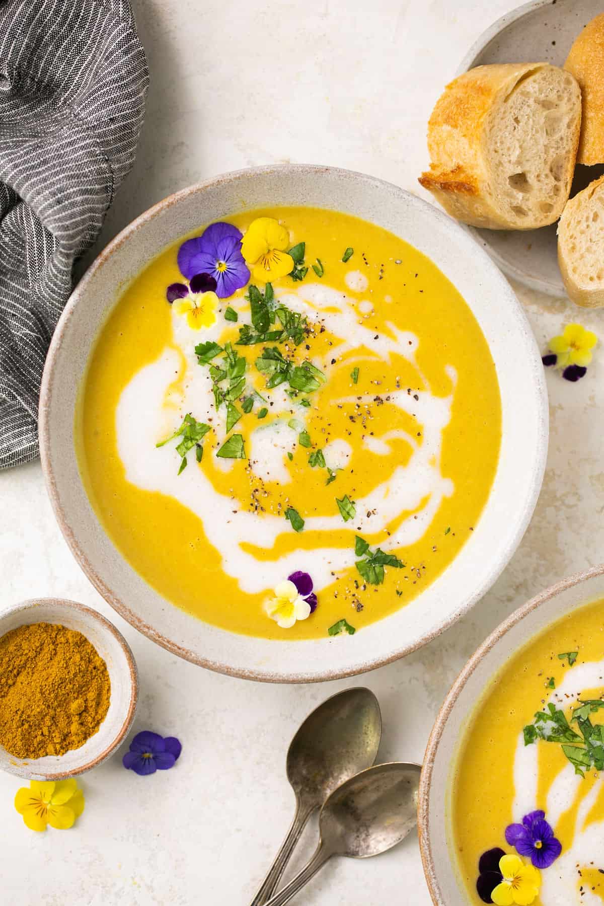 A bowl of curried squash soup garnished with flowers and coconut milk. 