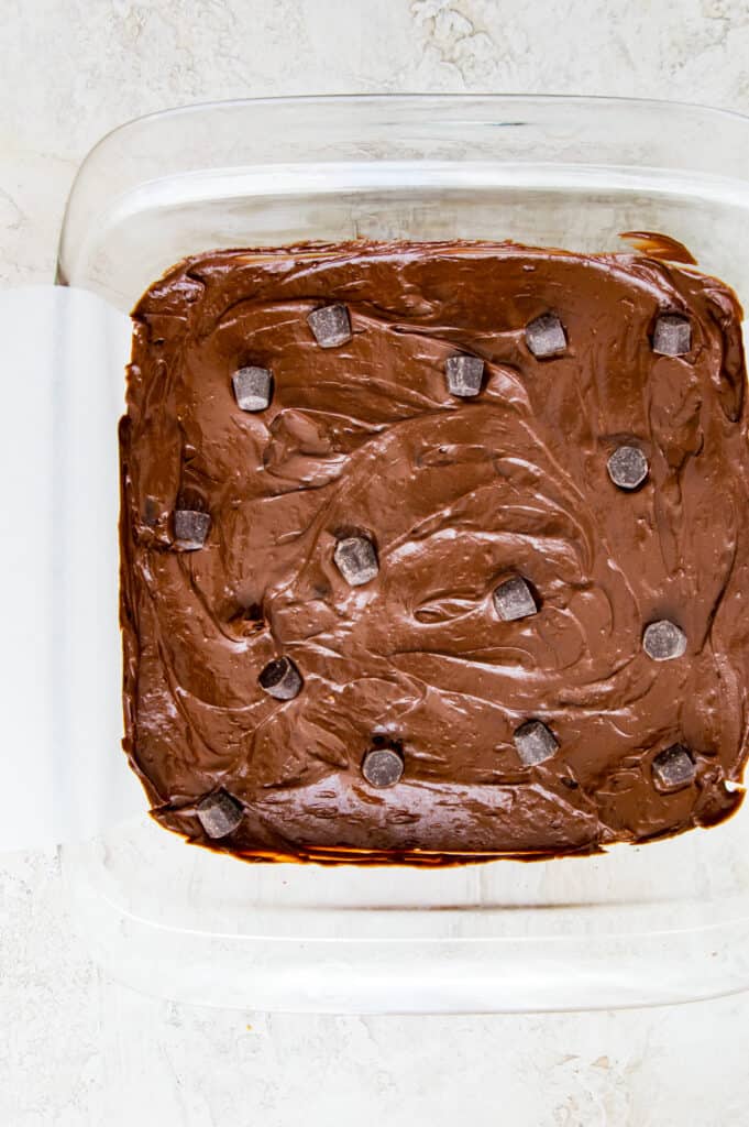 Avocado brownie batter in a pan topped with chocolate chips.