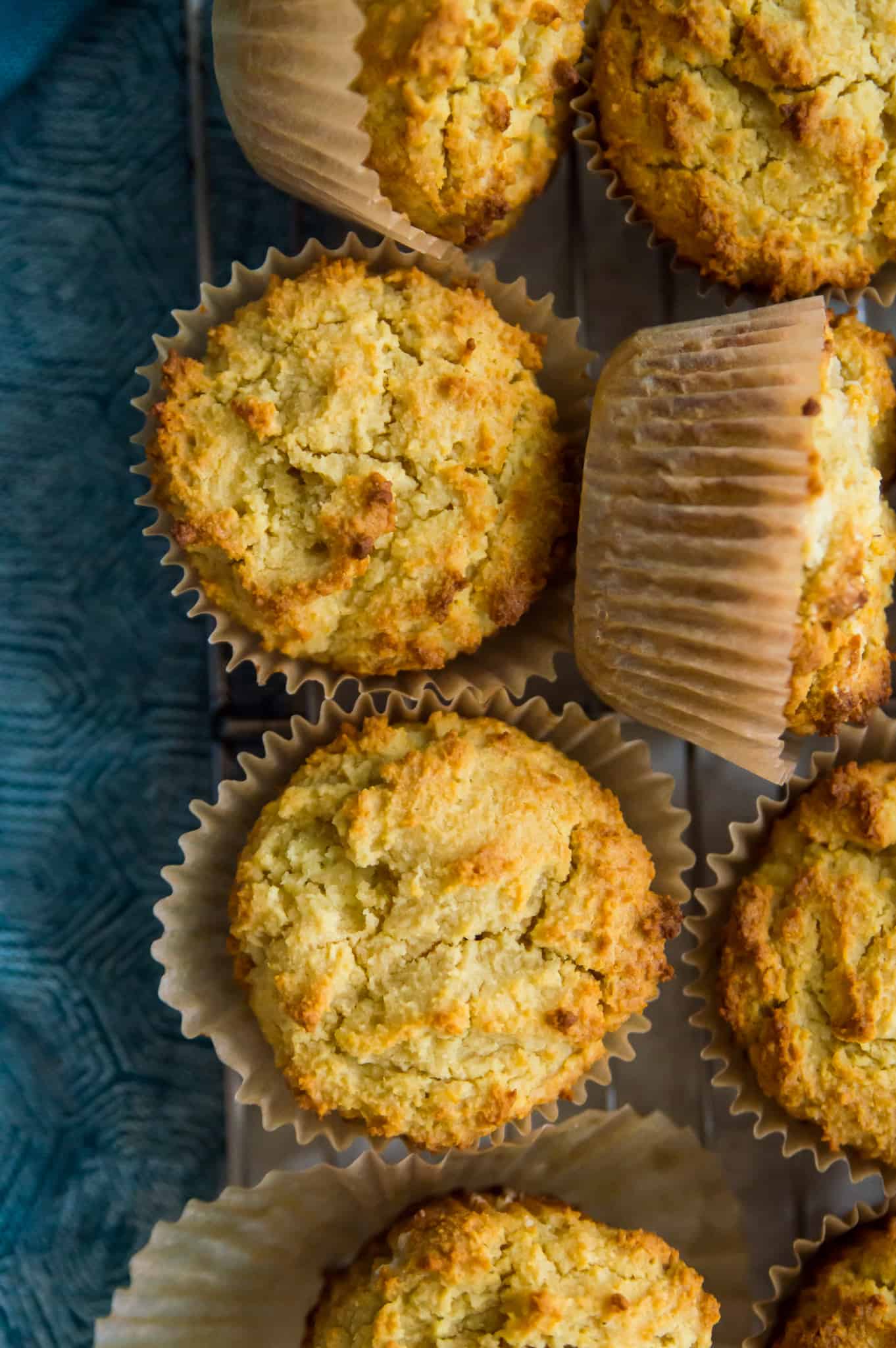 Paleo cornbread muffins on a wire rack with a blue tea towel beside it.