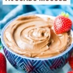 A bowl of chocolate avocado mousse with fresh strawberries around it.