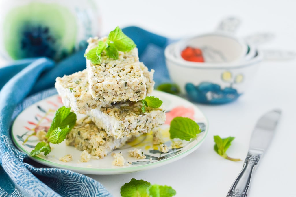 A stack of mint crunch bars on a plate with fresh mint leaves as garnish.