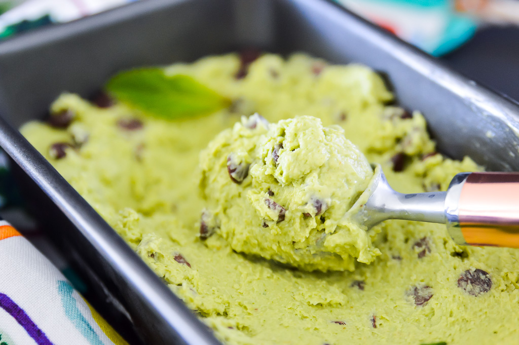 A bowl of avocado mint chip ice cream with an ice cream scoop