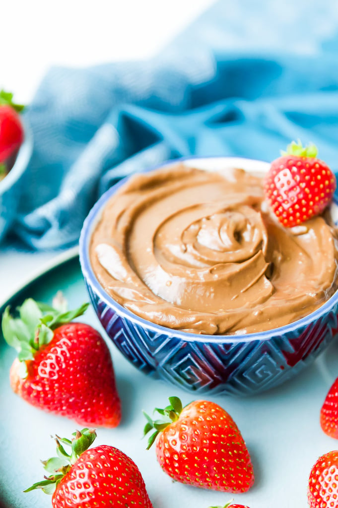 A bowl of vegan chocolate mousse with strawberries on top.