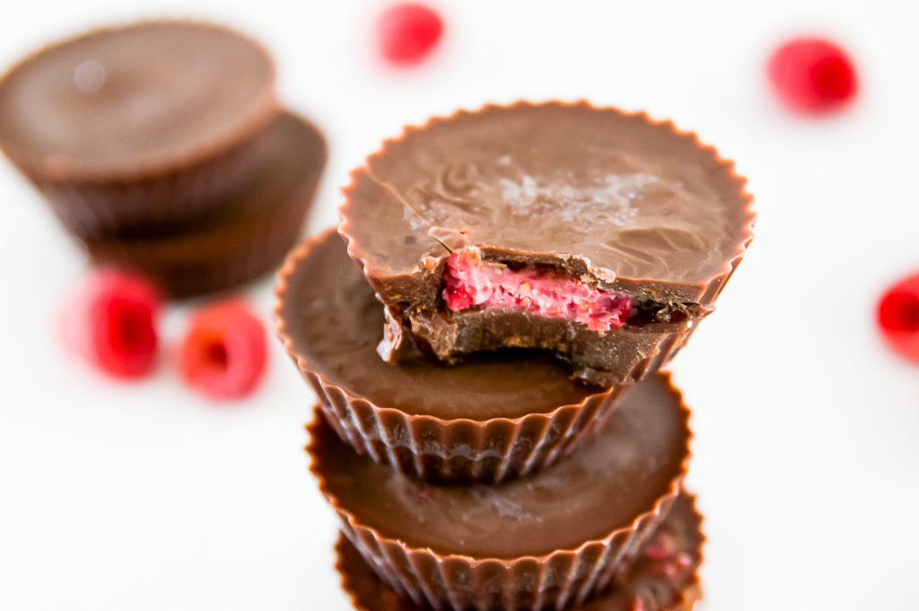 A pile of chocolate raspberry cups with a bite out of one