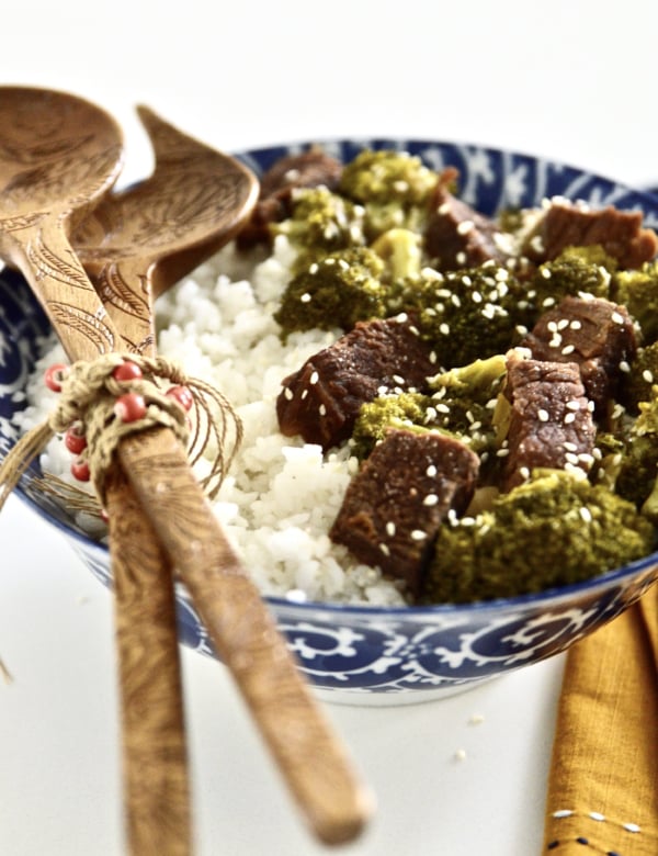 A large bowl of slow cooker beef and broccoli served with a side of white rice.