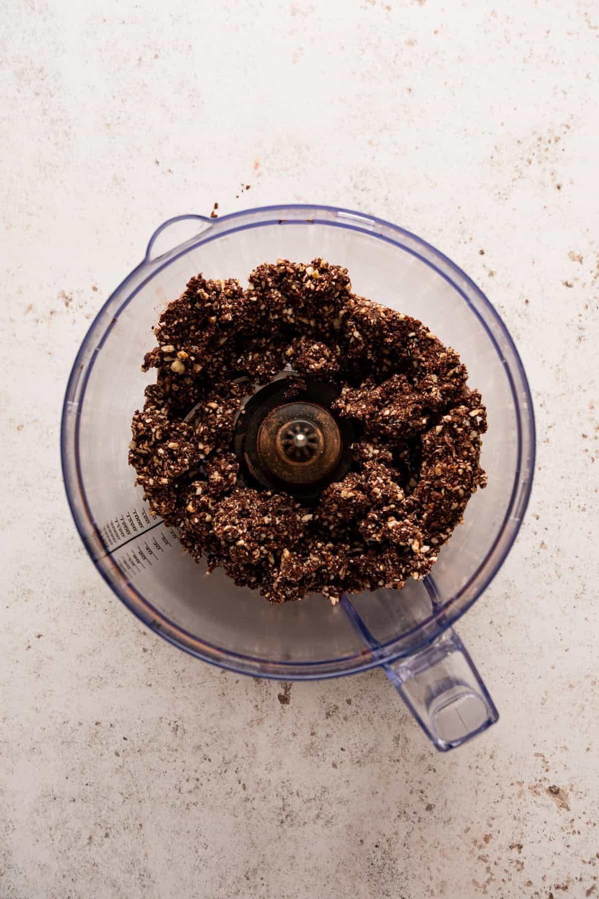 A food processor with a chocolate crumble mixture in it.