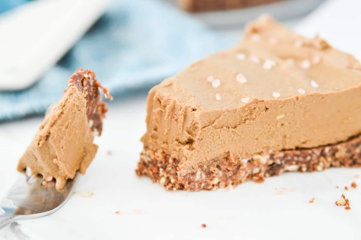 A piece of chocolate avocado torte on a plate with a bite out of it. 