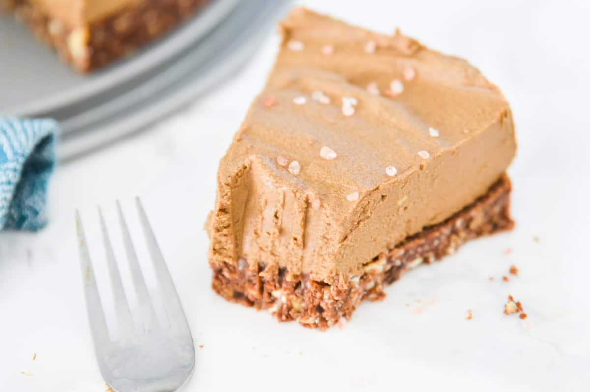 A piece of chocolate avocado torte on a plate with a bite out of it.