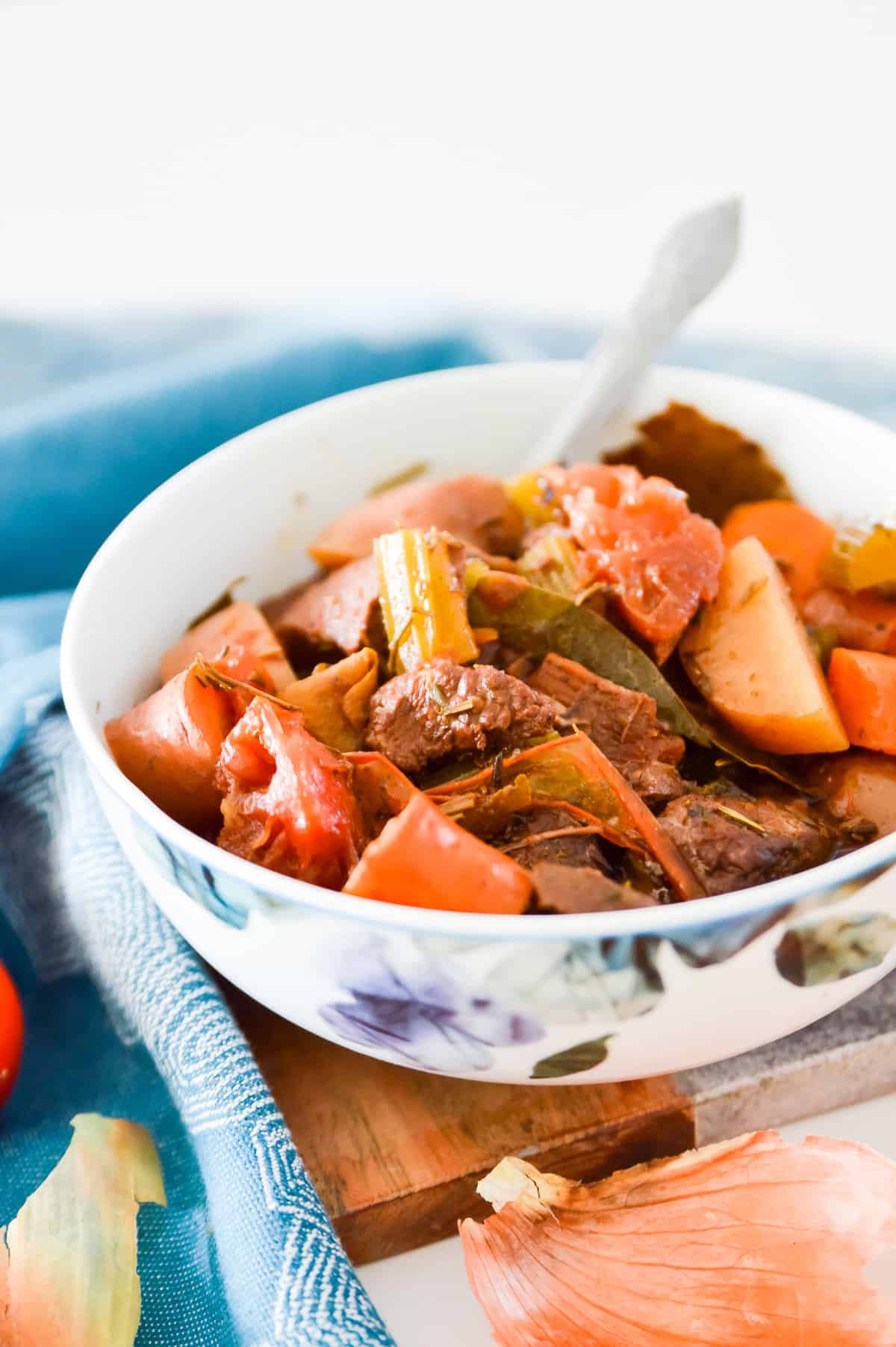 A bowl of beef stew with a spoon in it. 